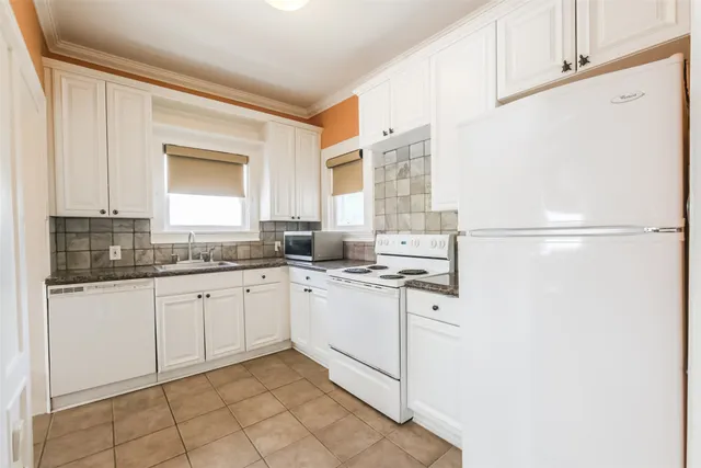 a kitchen with granite countertop white cabinets and white appliances