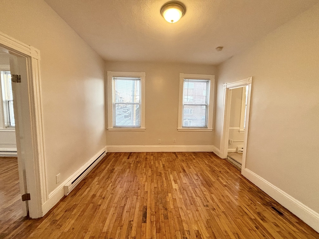 92 Main Street, Unit 1 Malden, MA 02148 - Photo 6 of 7 an empty room with wooden floor and windows