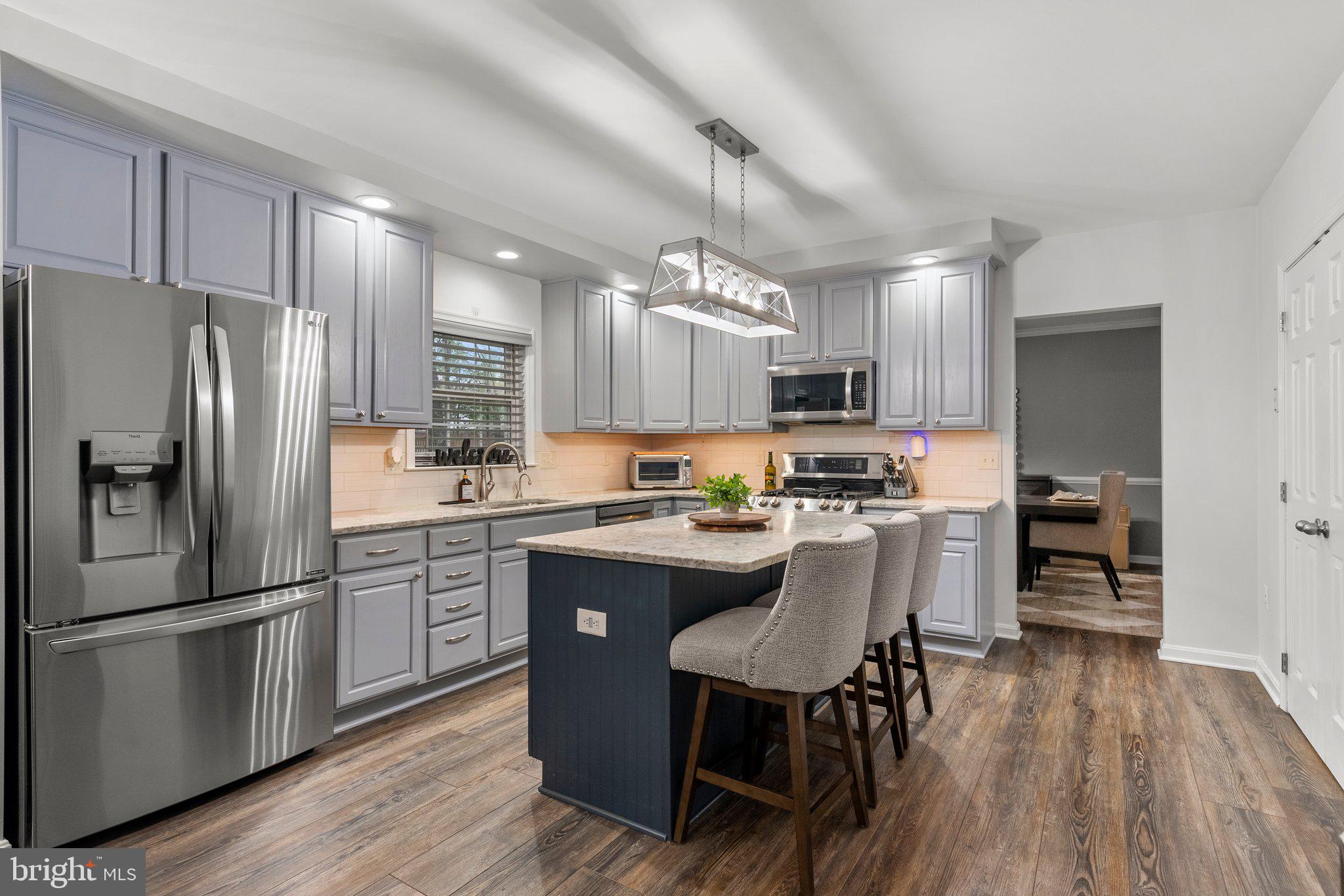 6355 Grant Chapman Drive La Plata, MD 20646 - Photo 15 of 57 a kitchen with kitchen island a refrigerator a stove a sink dishwasher a dining table and chairs with wooden floor