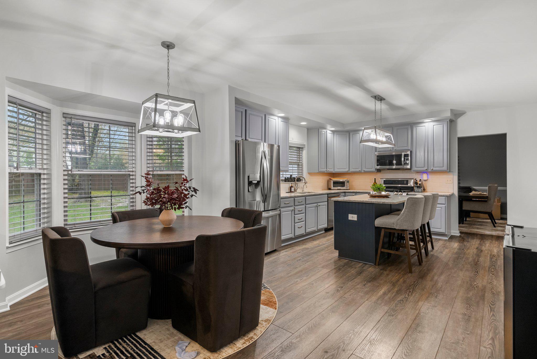 6355 Grant Chapman Drive La Plata, MD 20646 - Photo 21 of 57 a open dining room with stainless steel appliances kitchen island granite countertop a table chairs and a wooden floor