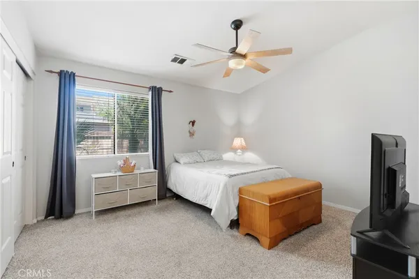a bedroom with a bed and a flat tv screen on dresser