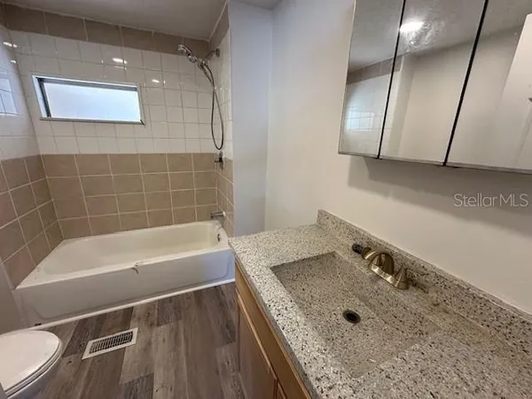 a bathroom with a granite countertop sink a toilet and bathtub