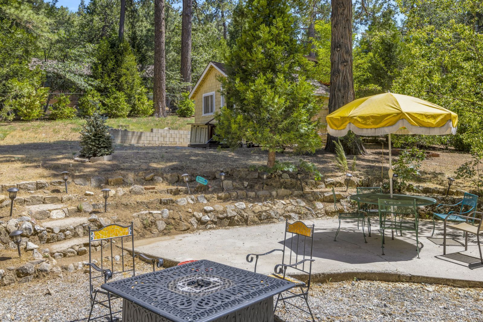 26770 Idyllwild Road Idyllwild, CA 92549 - Photo 50 of 56 a view of a backyard with table and chairs under an umbrella