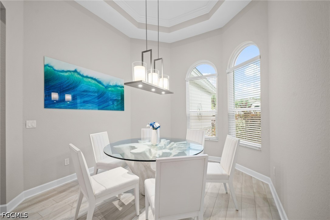 9042 Bronco Court Naples, FL 34113 - Photo 13 of 50 a view of a dining room with furniture a chandelier and wooden floor