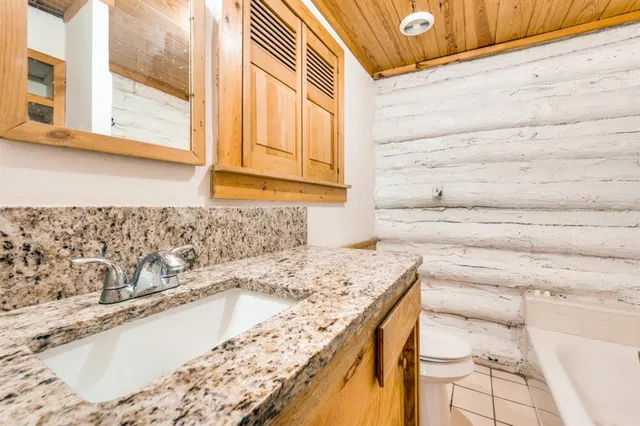 a spacious bedroom with a large bed a chandelier and windows