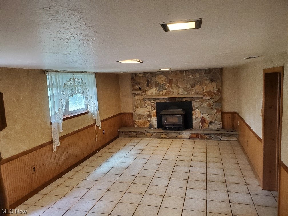 12221 Reno Drive Parma, OH 44130 - Photo 20 of 29 Unfurnished living room featuring light tile floors, a textured ceiling, a wood stove, and a fireplace