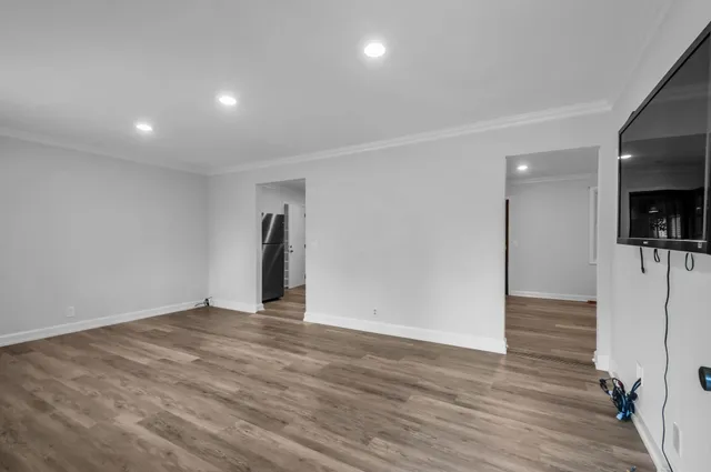 a view of an empty room with wooden floor and a flat screen tv