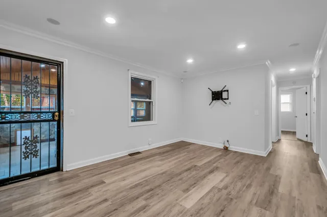 a view of an empty room with wooden floor and a window