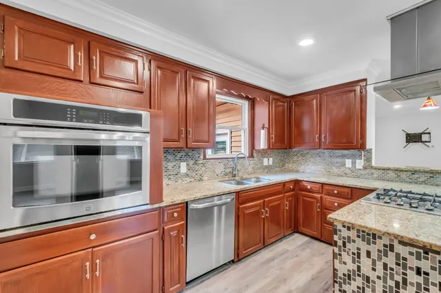 a kitchen with stainless steel appliances granite countertop wooden cabinets and a stove top oven