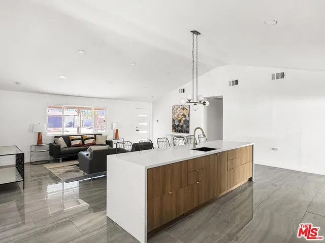 a kitchen with kitchen island a counter top space a sink a refrigerator and a stove