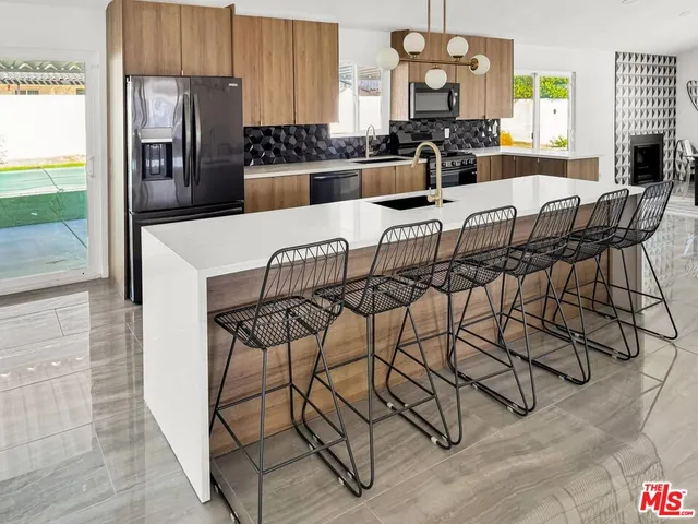 a kitchen with stainless steel appliances granite countertop a refrigerator a sink a stove and chairs