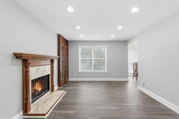 a view of an empty room with wooden floor fireplace and a window