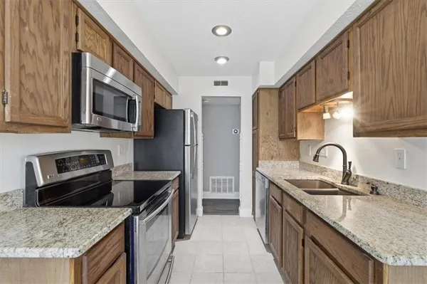 a kitchen with stainless steel appliances granite countertop a sink stove microwave refrigerator and cabinets