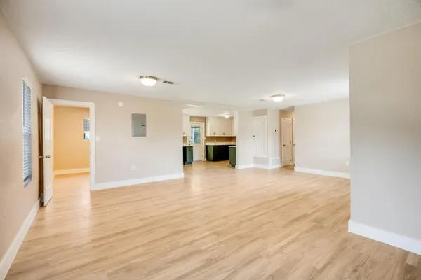 a view of empty room with wooden floor and kitchen