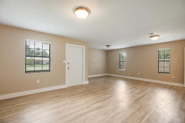 an empty room with wooden floor and windows