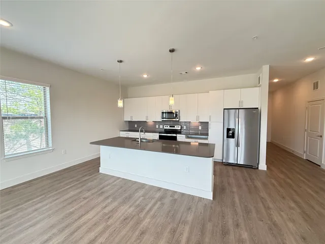 a large white kitchen with wooden floors and stainless steel appliances