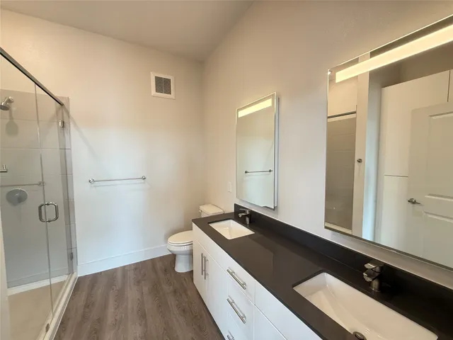 a view of a bathroom with a double vanity sink a toilet and a shower