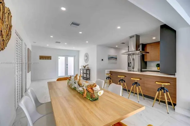 a room with stainless steel appliances furniture a rug and a kitchen view