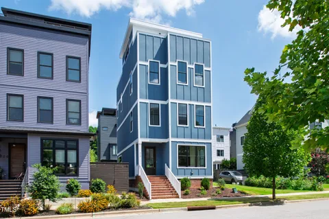 a front view of a multi story residential apartment building with yard and parking space