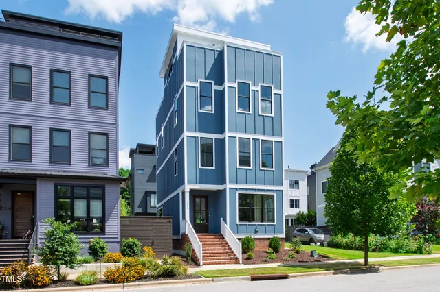 a front view of a multi story residential apartment building with yard and parking space