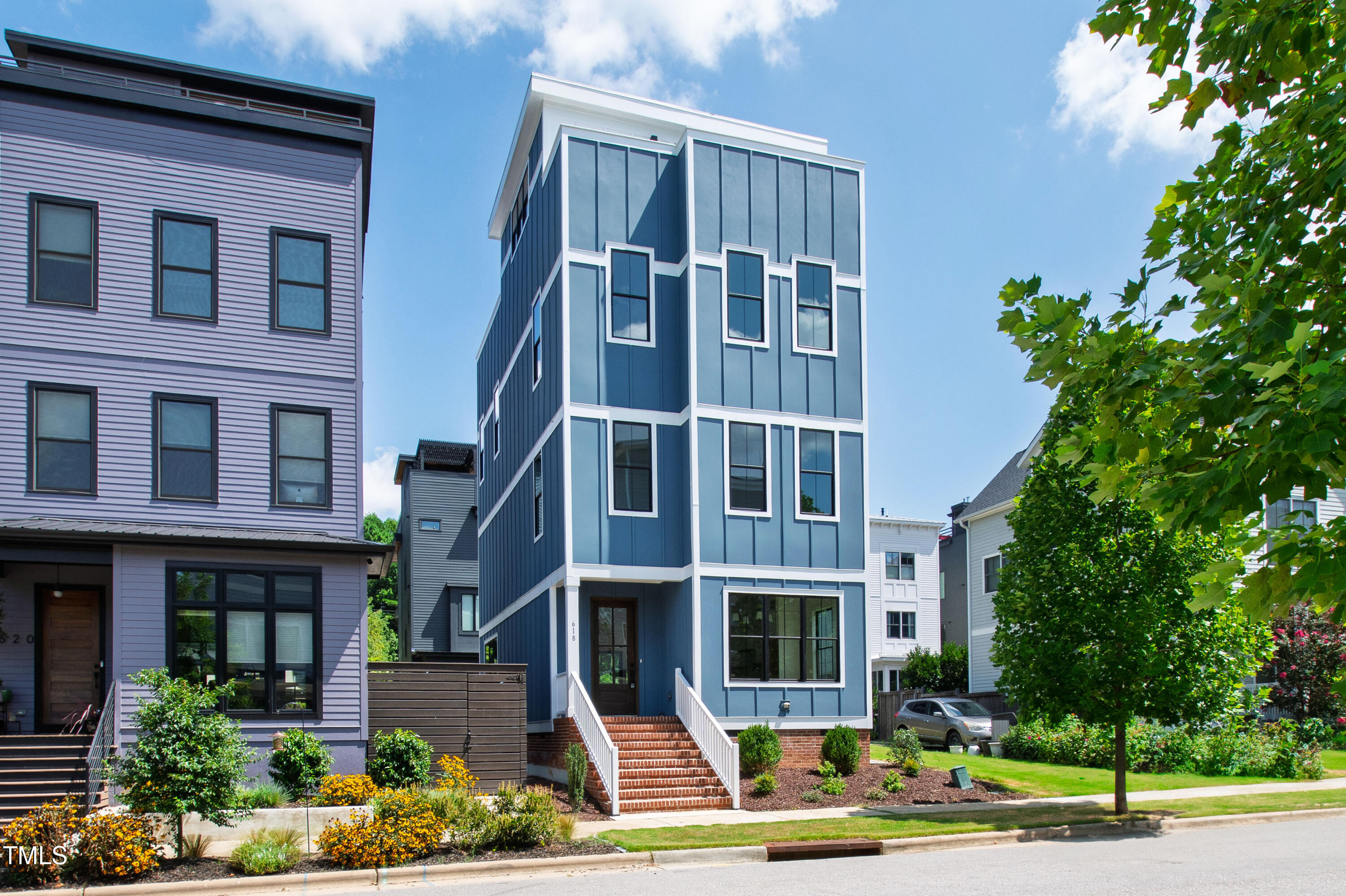 a front view of a multi story residential apartment building with yard and parking space