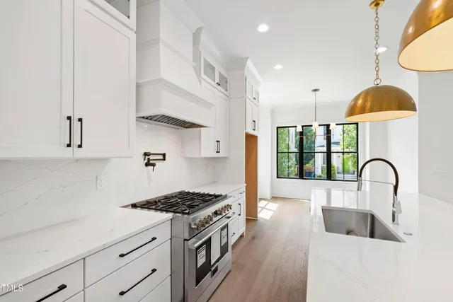 a kitchen with white cabinets appliances and a window