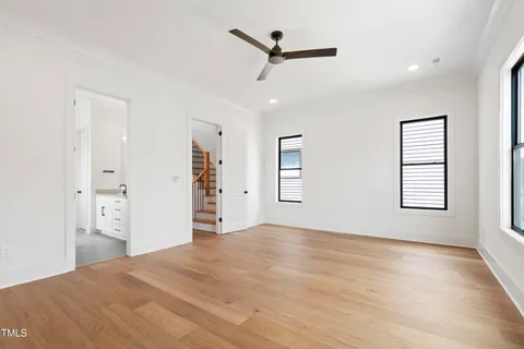 a view of empty room with wooden floor and ceiling fan