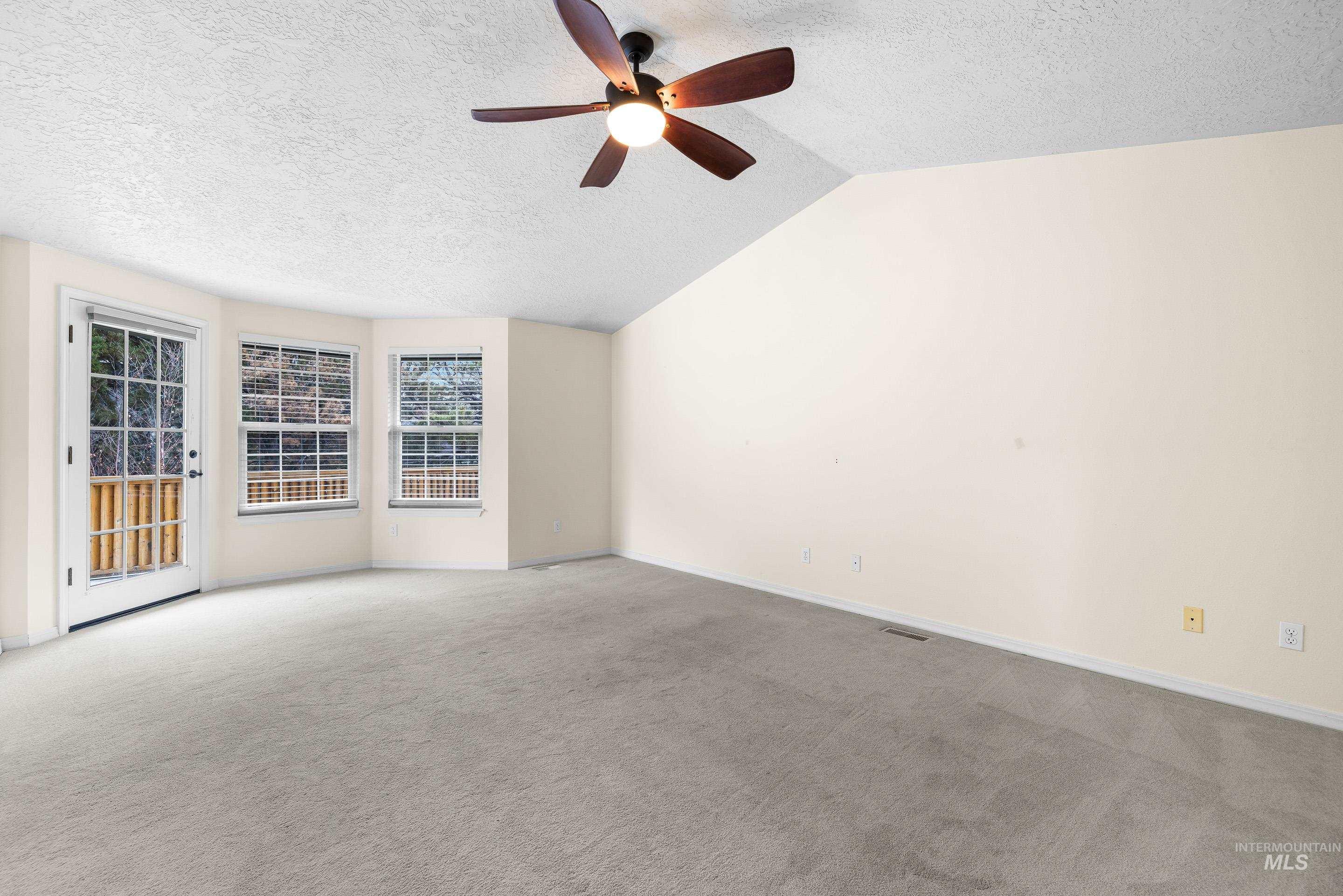 7736 West Bayhill Street Boise, ID 83704 - Photo 25 of 50 Spare room featuring a textured ceiling, light colored carpet, vaulted ceiling, and ceiling fan