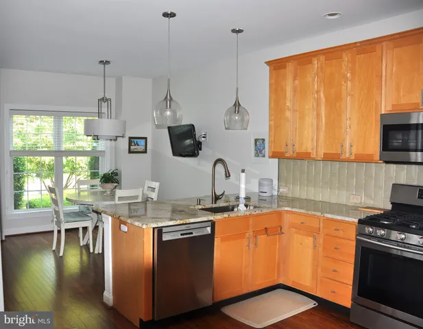 a kitchen with stainless steel appliances granite countertop a sink a stove and a wooden cabinets