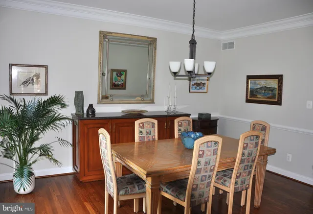 a dining room with wooden floor a chandelier a wooden table and chairs