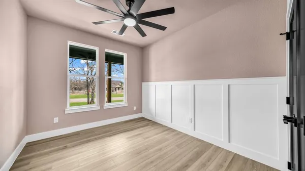 an empty room with wooden floor closet and windows