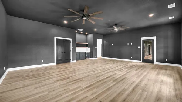 a view of an empty room with wooden floor and a ceiling fan