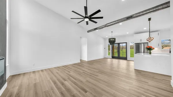 a view of empty room with wooden floor and ceiling fan