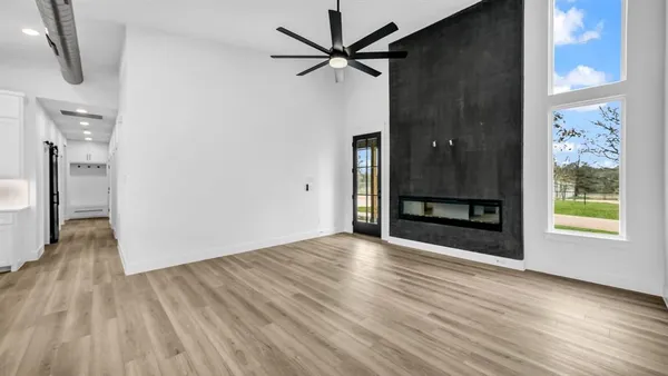 a view of a livingroom with wooden floor a ceiling fan and windows