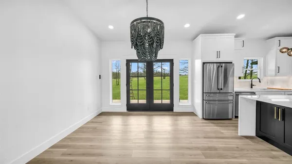 a kitchen with stainless steel appliances granite countertop a refrigerator and a wooden floor