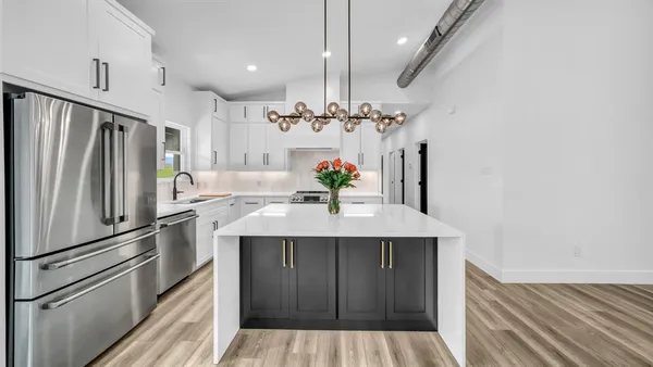 a kitchen with kitchen island granite countertop a sink cabinets and stainless steel appliances