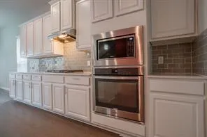 a kitchen with granite countertop white cabinets stainless steel appliances and a sink