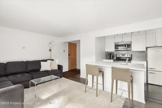 a living room with furniture and a refrigerator