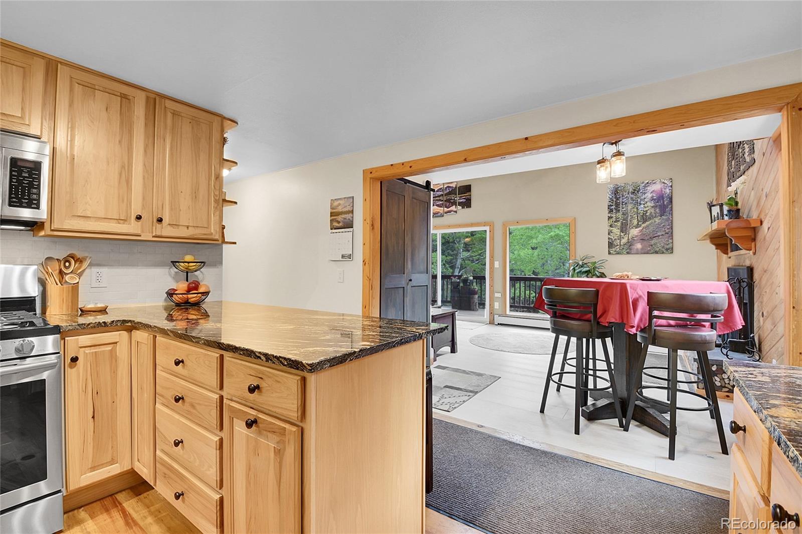 11182 Barney Gulch Road Conifer, CO 80433 - Photo 15 of 50 a open kitchen with stainless steel appliances granite countertop a stove top oven a sink a dining table and chairs with wooden floor
