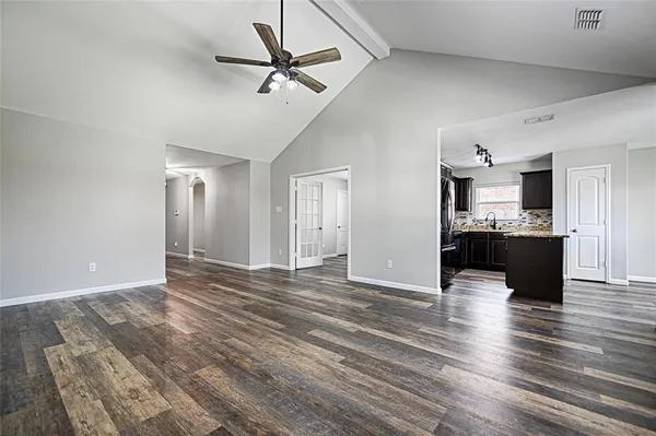 an empty room with wooden floor fan and windows