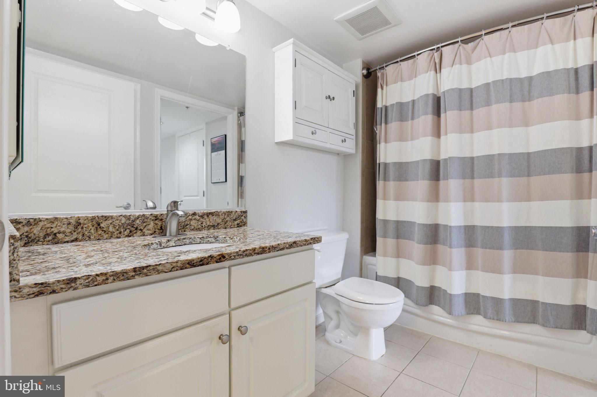 11800 Sunset Hills Road, Unit 218 Reston, VA 20190 - Photo 24 of 38 a bathroom with a granite countertop sink a toilet and a mirror