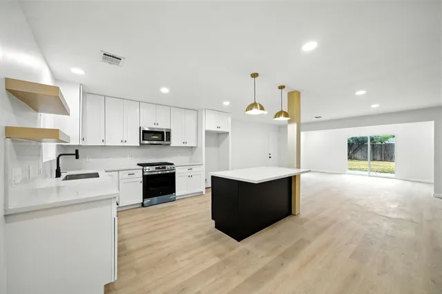 a large kitchen with stainless steel appliances granite countertop a stove a sink and a refrigerator