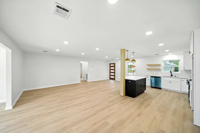 a large white kitchen with a stove a sink dishwasher and a refrigerator with wooden floor