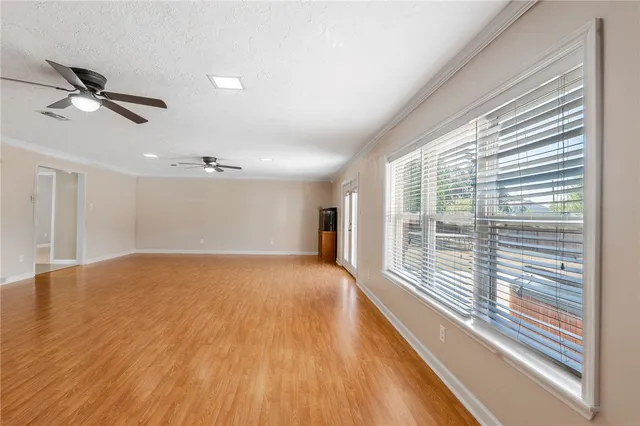 a view of an empty room with a window and wooden floor