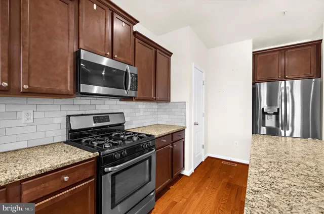 a kitchen with stainless steel appliances granite countertop a stove microwave and refrigerator