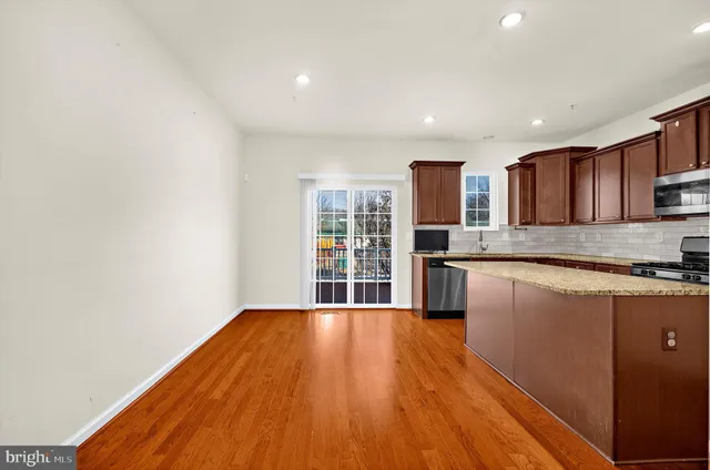a kitchen with granite countertop wooden floors stainless steel appliances and a window