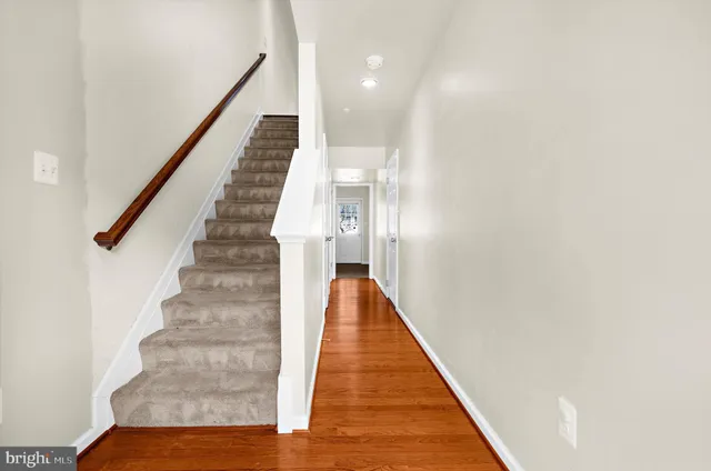 a view of a hallway with wooden floor and staircase