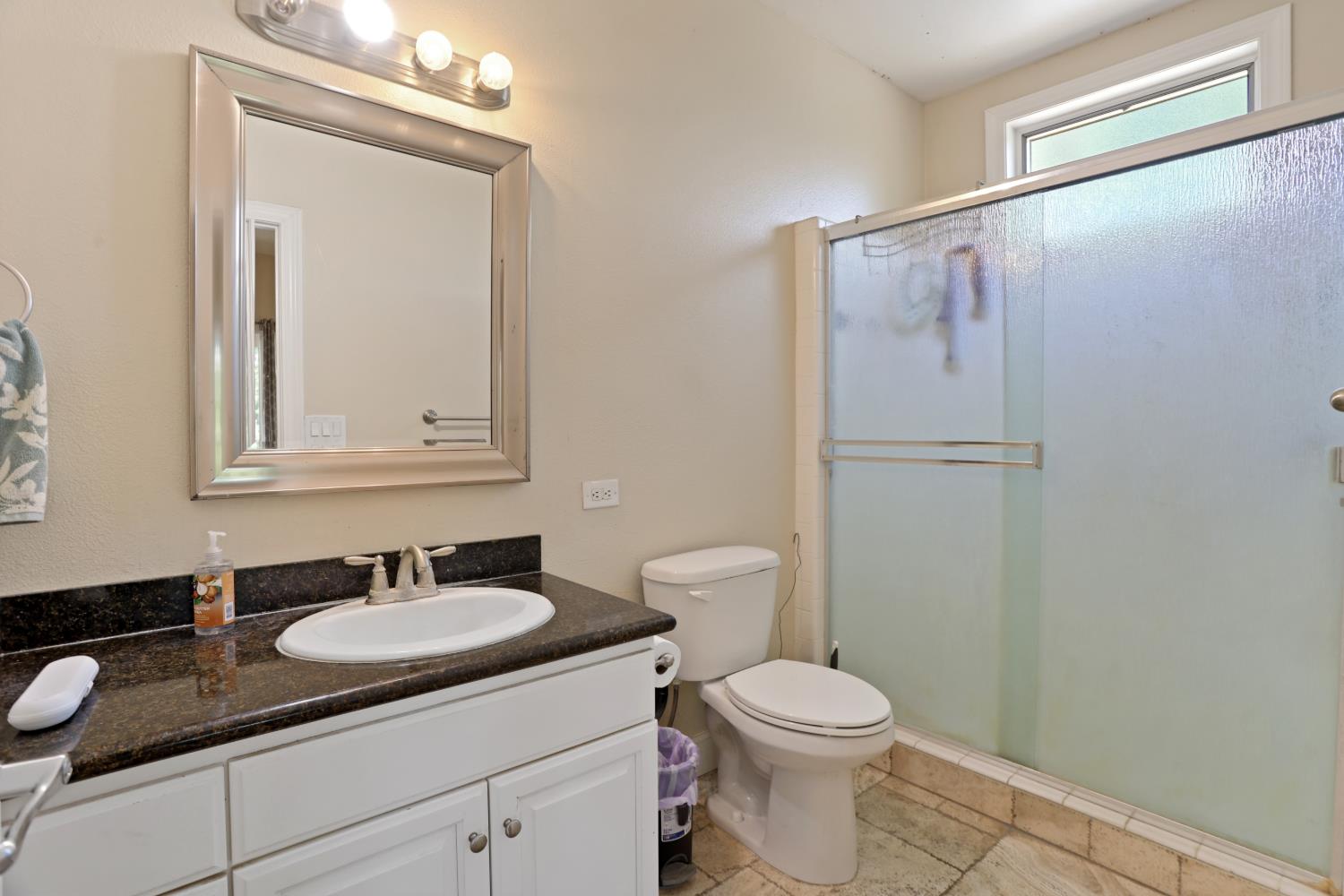 9935 Hazel Road Stockton, CA 95212 - Photo 46 of 98 a bathroom with a granite countertop sink toilet and a mirror