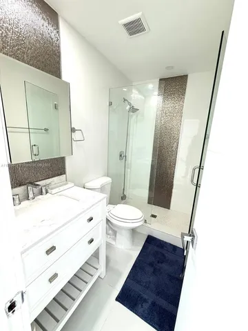 a bathroom with a sink a toilet a mirror and shower