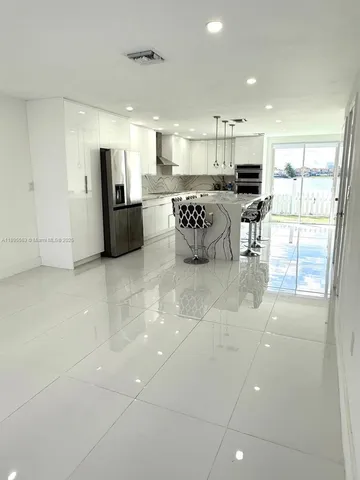 a kitchen with stainless steel appliances kitchen island granite countertop a refrigerator and a stove top oven